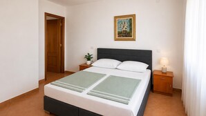 A neatly arranged bedroom with a bed, bedside tables, a nightstand, a framed picture, and a door. - 2 bedroom stunning apartment in Preko (Preko)