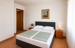 A neatly arranged bedroom with a bed, bedside tables, a nightstand, a framed picture, and a door. - 2 bedroom stunning apartment in Preko (Preko)
