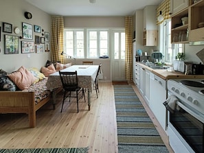 Eine gemütliche Küche mit Holzausstattung, einem Esstisch und einer Couch.