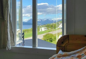 A room with a large window offering a view of a mountain and a body of water. - Old parish hall in Kvæfjord (Borkenes)