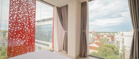 Una habitación de hotel con un ventanal grande, una cama y cortinas.