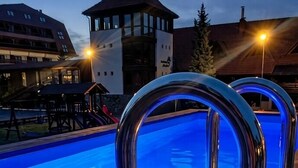 Une piscine avec deux coupes à champagne et une lanterne, entourée d’une terrasse en bois et d’un bâtiment doté d’une tour.