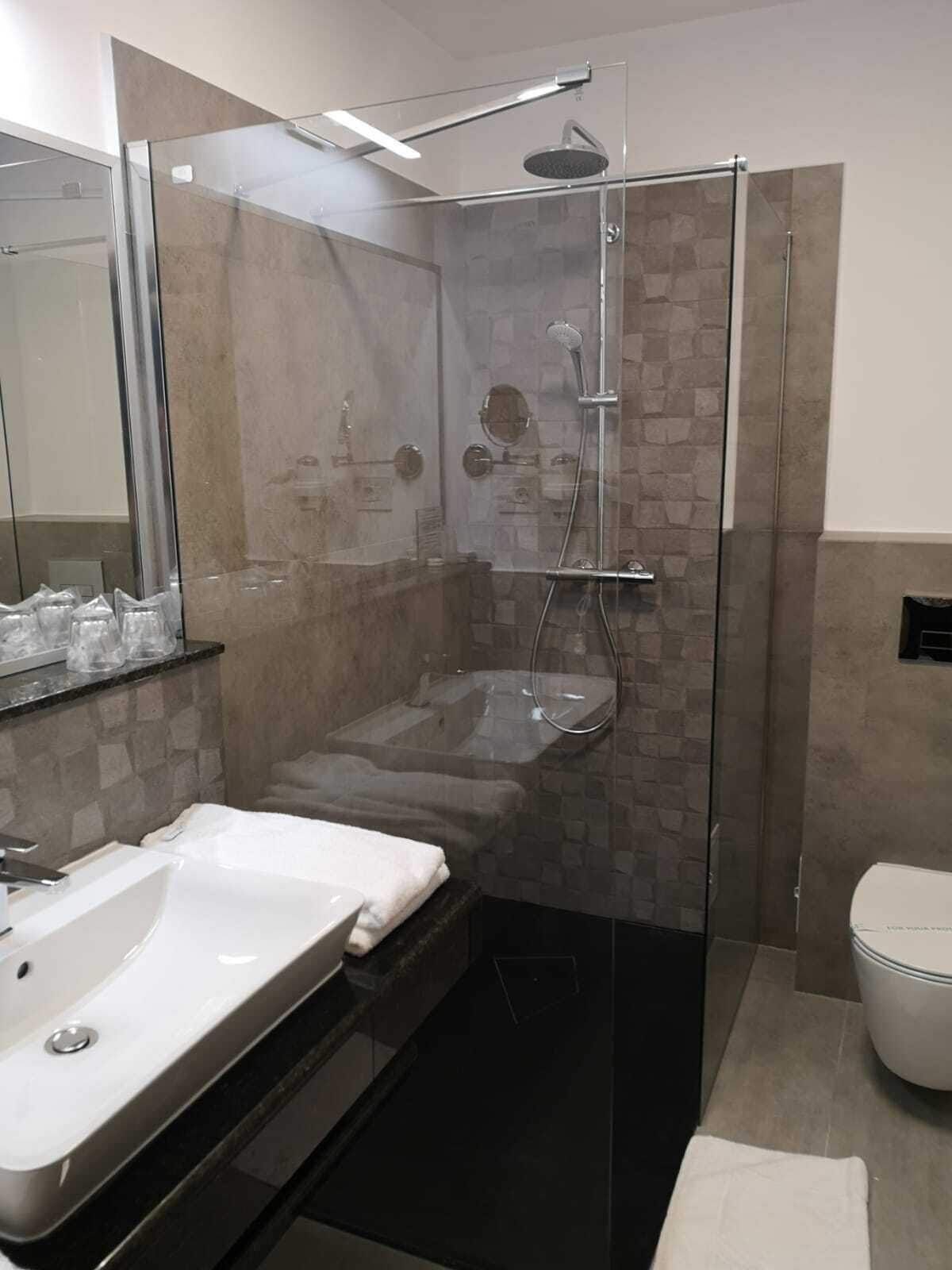 Une salle de bain moderne avec une douche à parois de verre, un lavabo blanc et des toilettes.