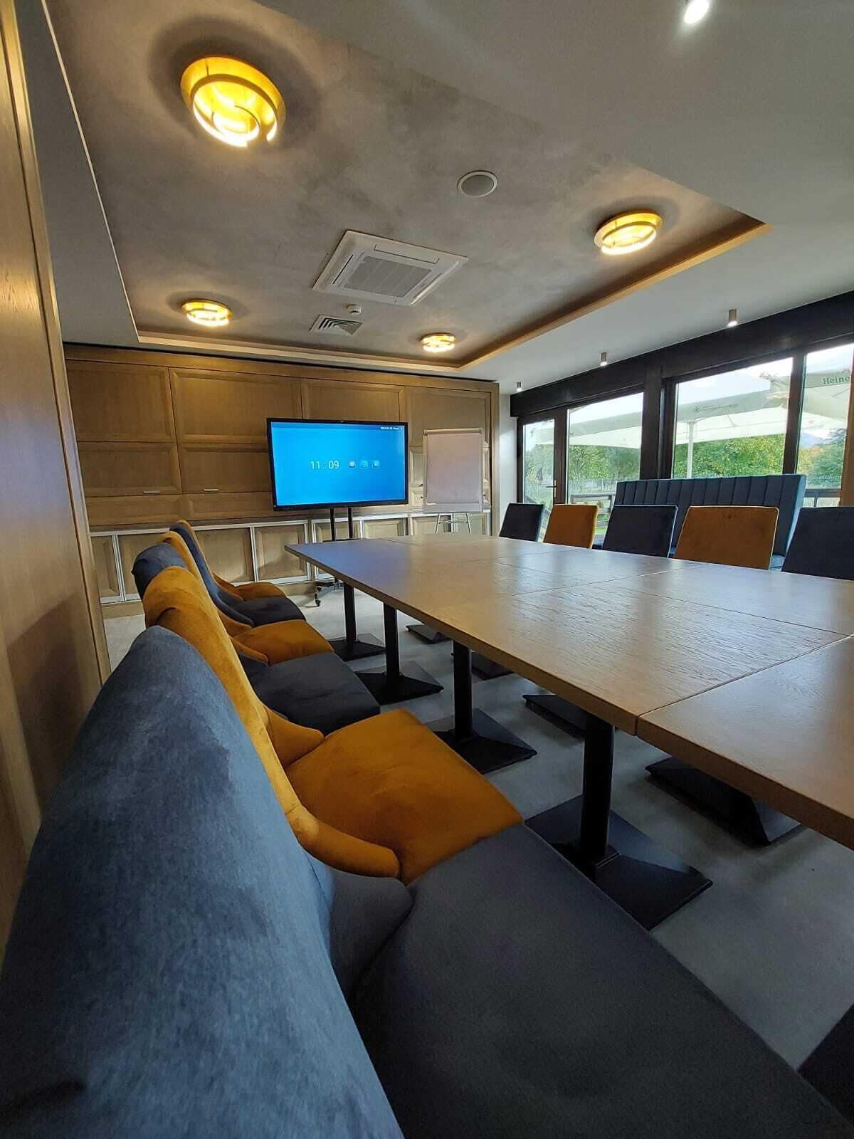 A conference room with a long table, multiple chairs, a large screen, and a whiteboard.
