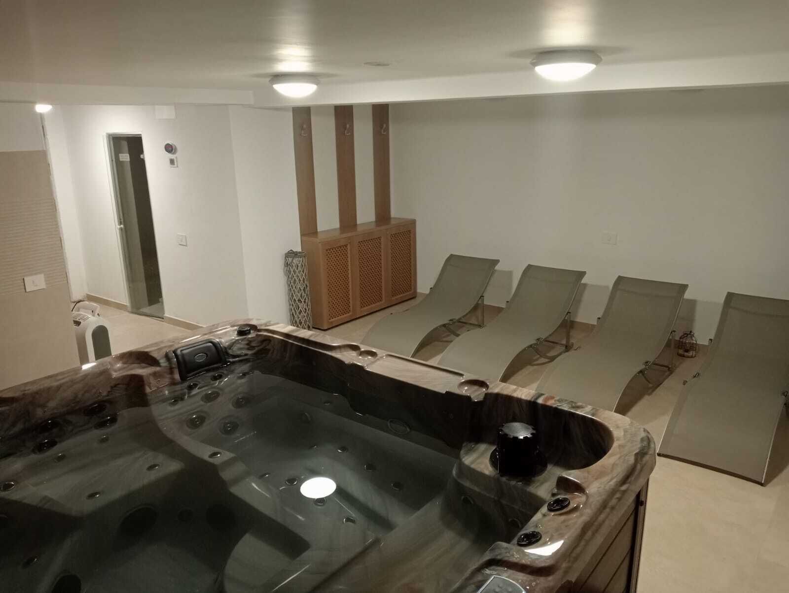 Un'area benessere con vasca idromassaggio, sedie a sdraio e sauna.