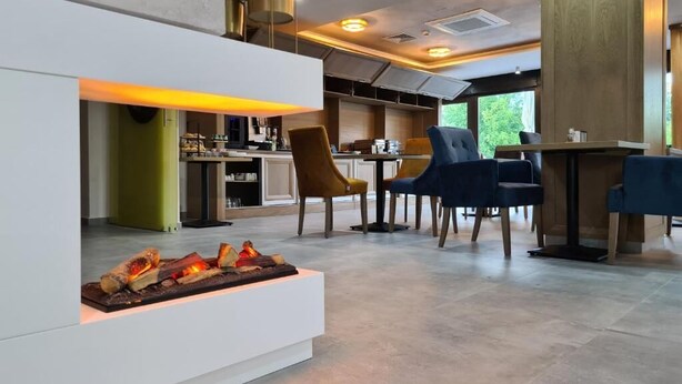 Un intérieur moderne avec une cheminée, un coin salon et une cuisine en arrière-plan.