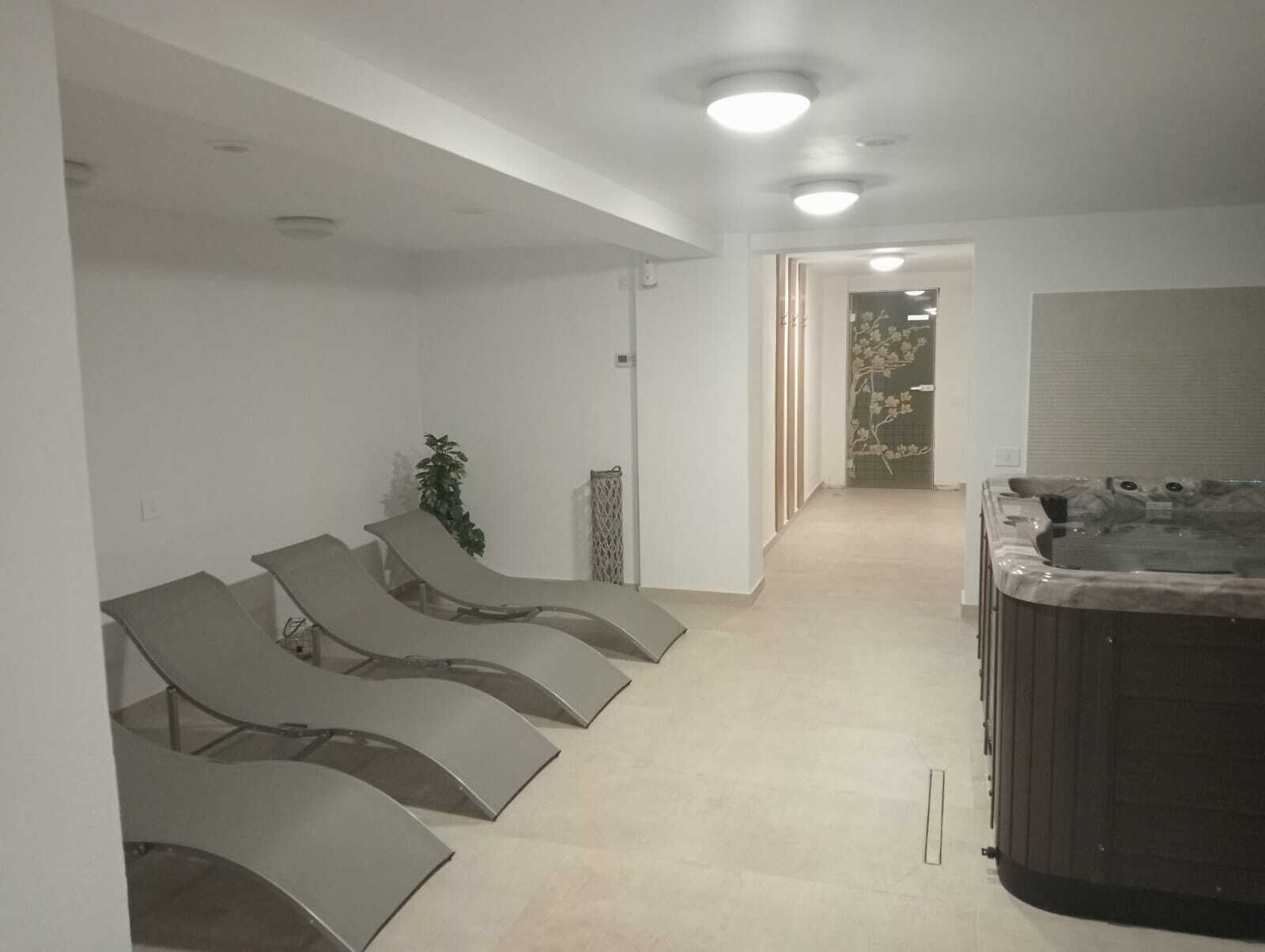 Un área de spa con sillones reclinables, un jacuzzi y un pasillo que conduce a otra habitación.
