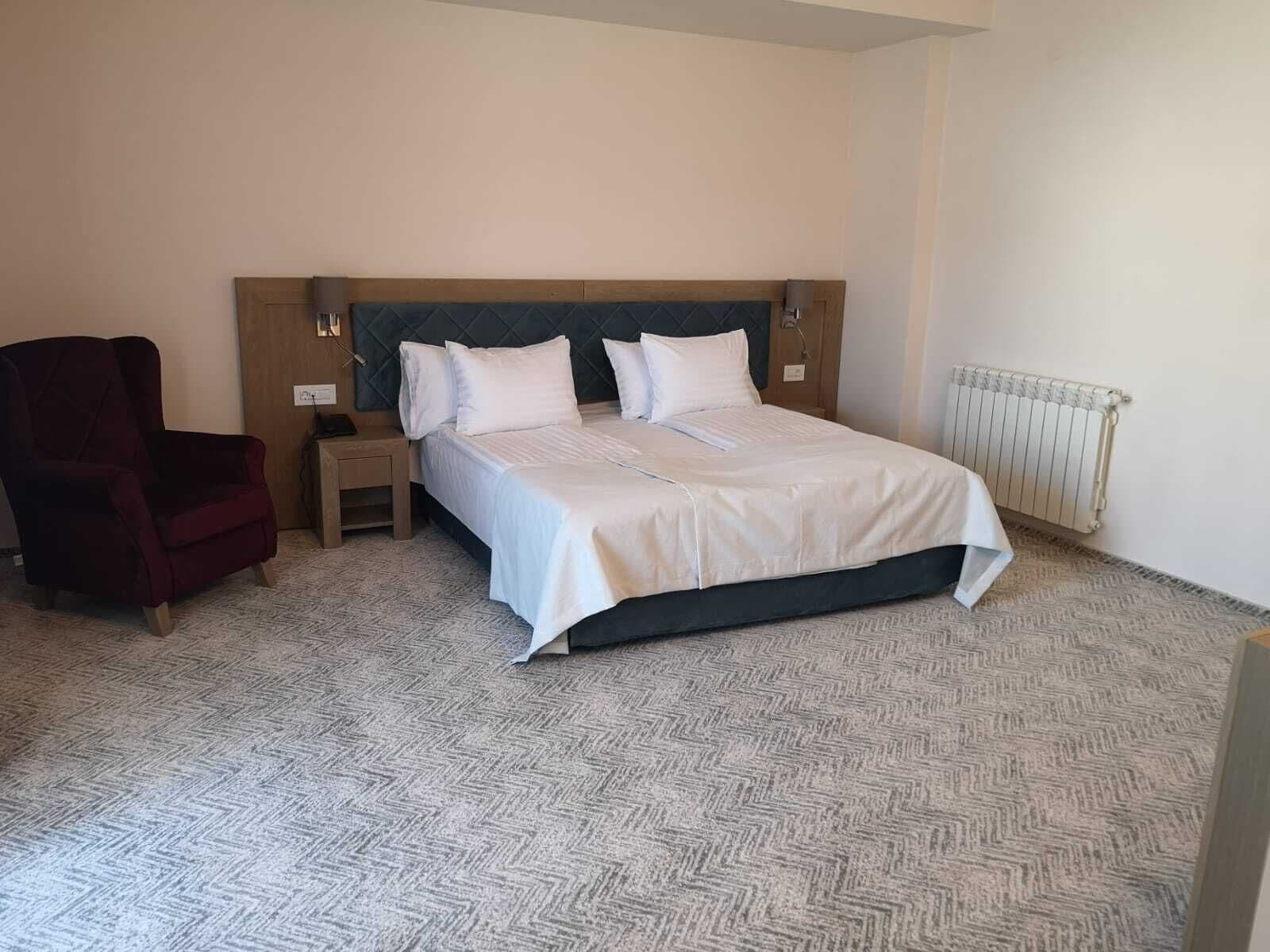 Ein Schlafzimmer mit einem Bett, einem Nachttisch, einem Sessel und einer Heizung.
