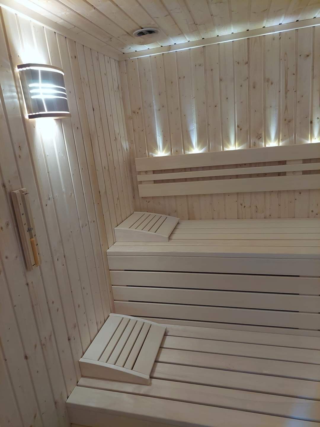 Una sauna con bancos de madera y un accesorio de luz en la pared.