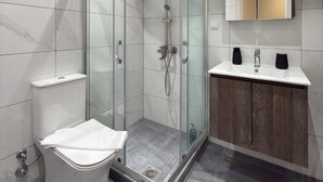 A modern bathroom with a glass-enclosed shower, a toilet, and a vanity with a mirror. - SmartLiving Central Apt 8 (Thessaloniki)