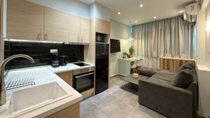 A modern kitchen with a built-in oven, a coffee maker, and a dining area with a table and chairs. - SmartLiving Central Apt 8 (Thessaloniki)