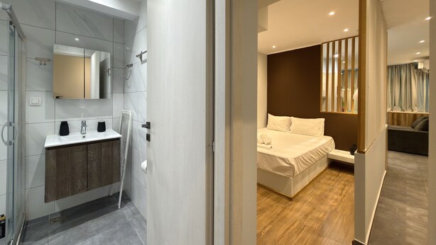 A modern hotel room with a bathroom, a bed, and a view of the outside. - SmartLiving Central Apt 8 (Thessaloniki)