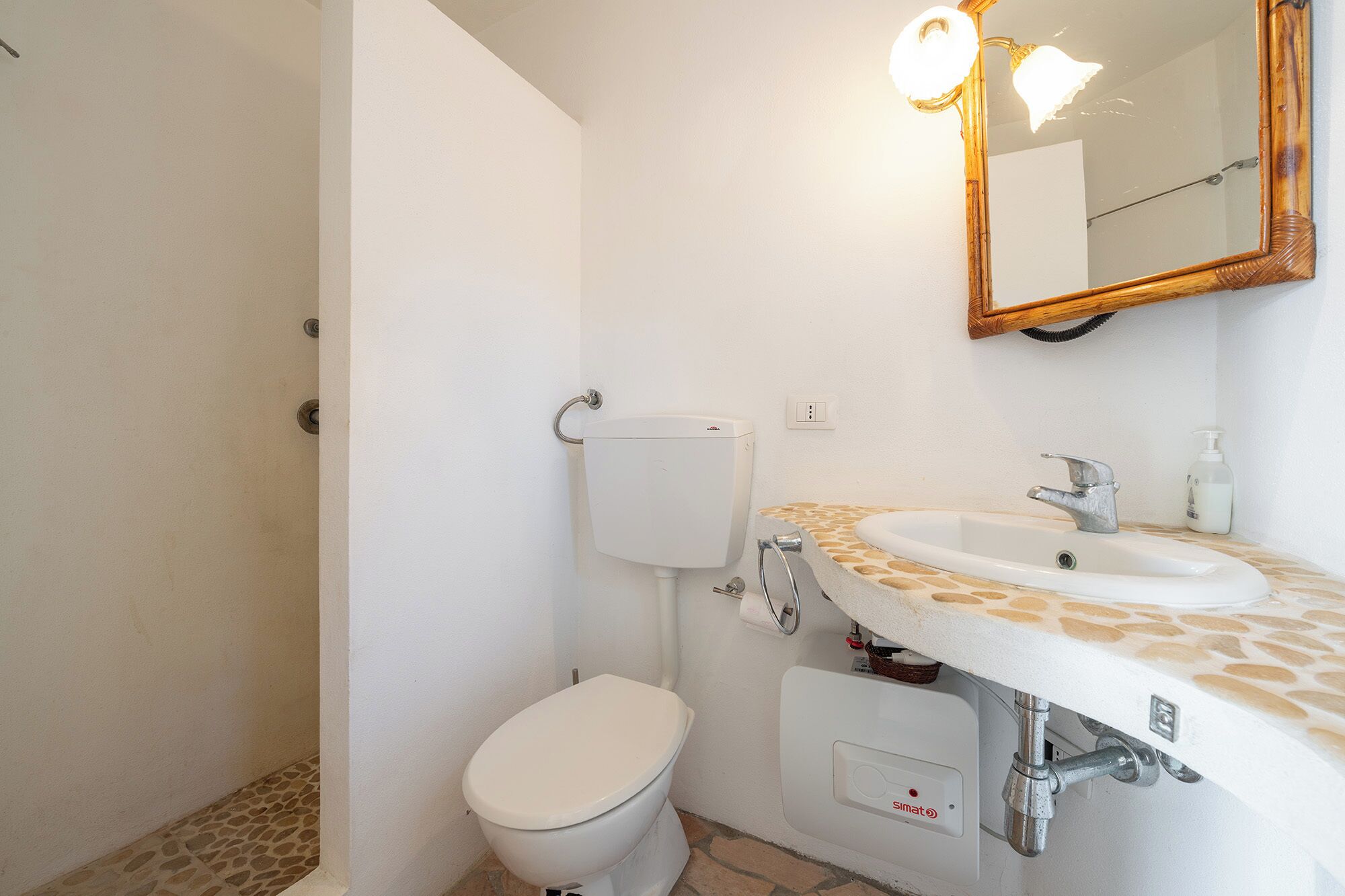 A bathroom with a toilet, sink, and mirror.