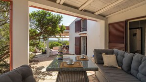 An outdoor seating area with a glass table, wicker chairs, and a sofa.