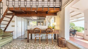 A rustic dining area with a wooden table, two chairs, a mirror, and a view of the outdoors.