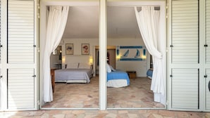 A room with a bed, a blue bedspread, and a painting on the wall.