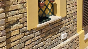 Una ventana con un diseño de celosía, plantas en macetas y un muro de piedra.