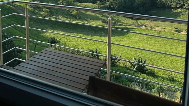 En balkong med utsikt över ett grönskande landskap och avlägsna berg.