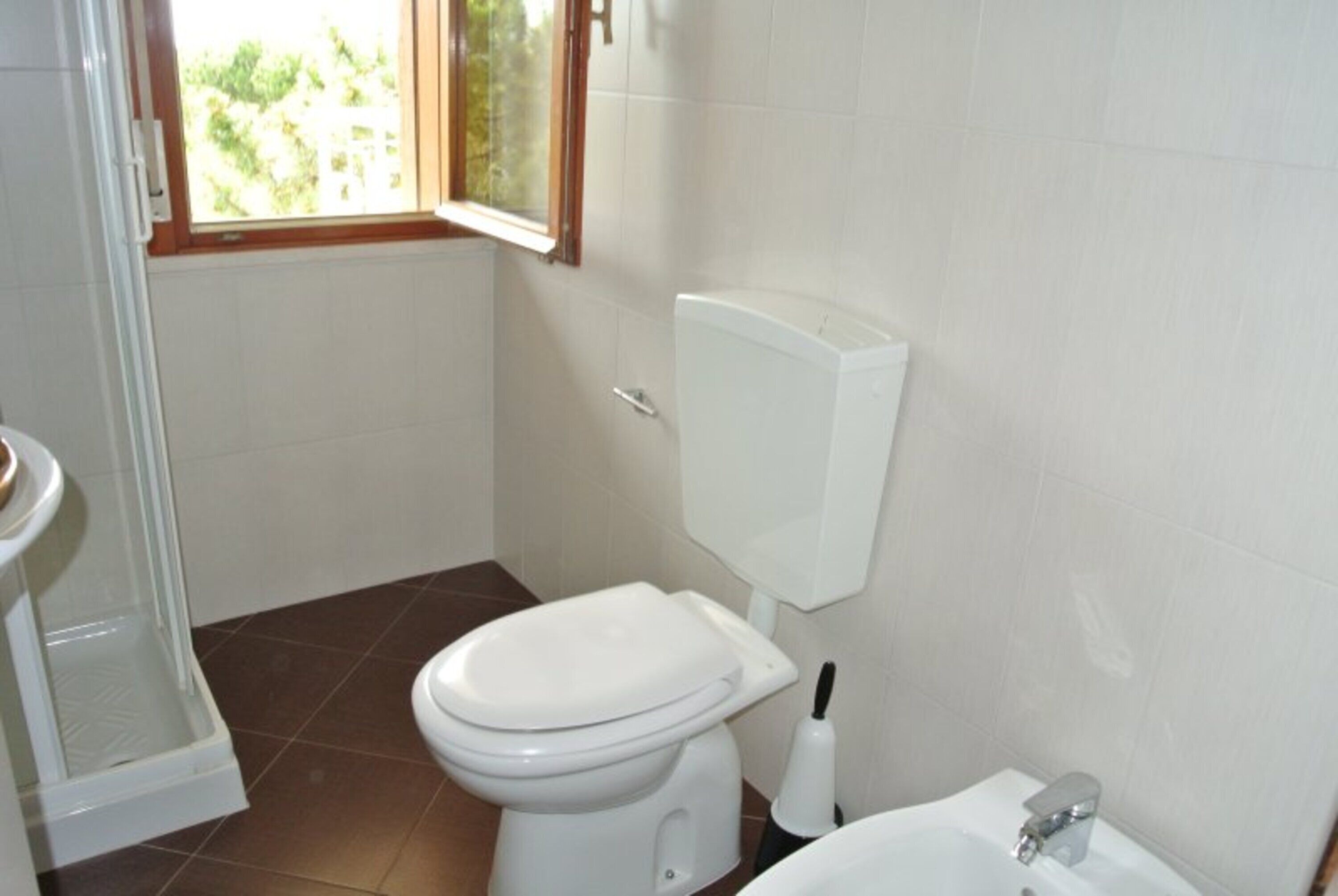 A bathroom with a toilet, bidet, and shower.