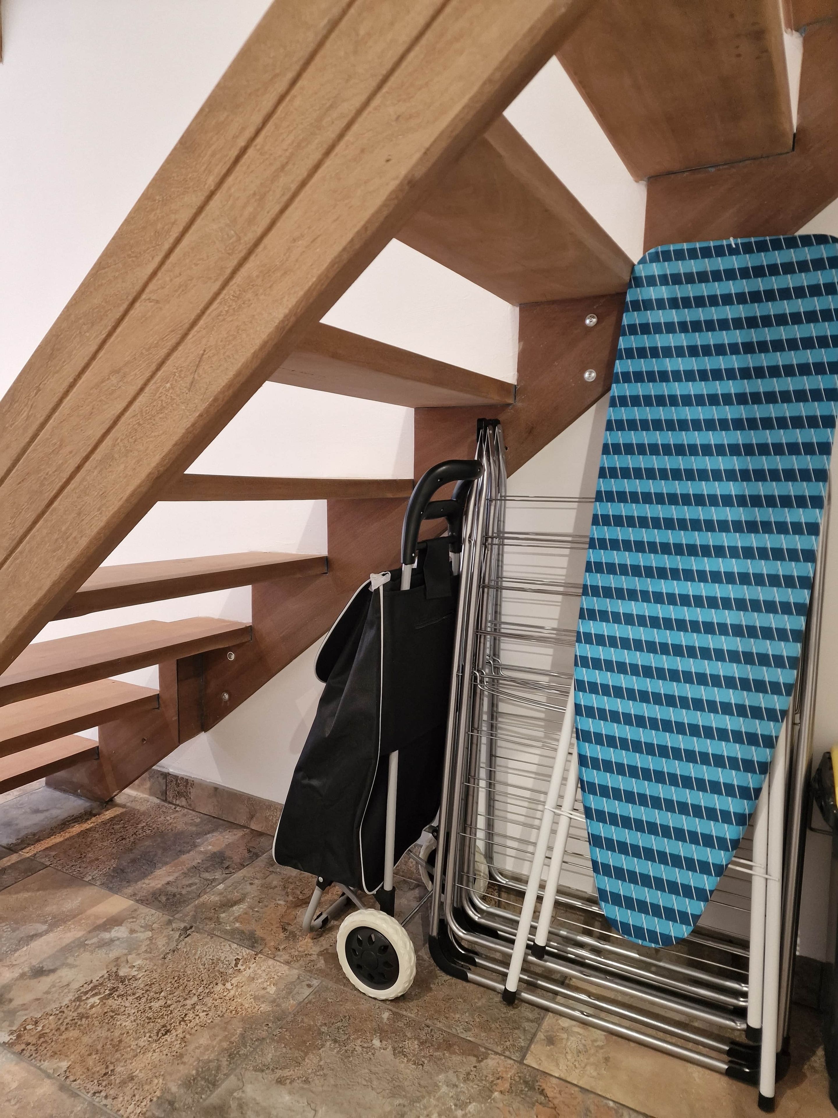 Een houten trap met een metalen wasrek en een zwarte tas.