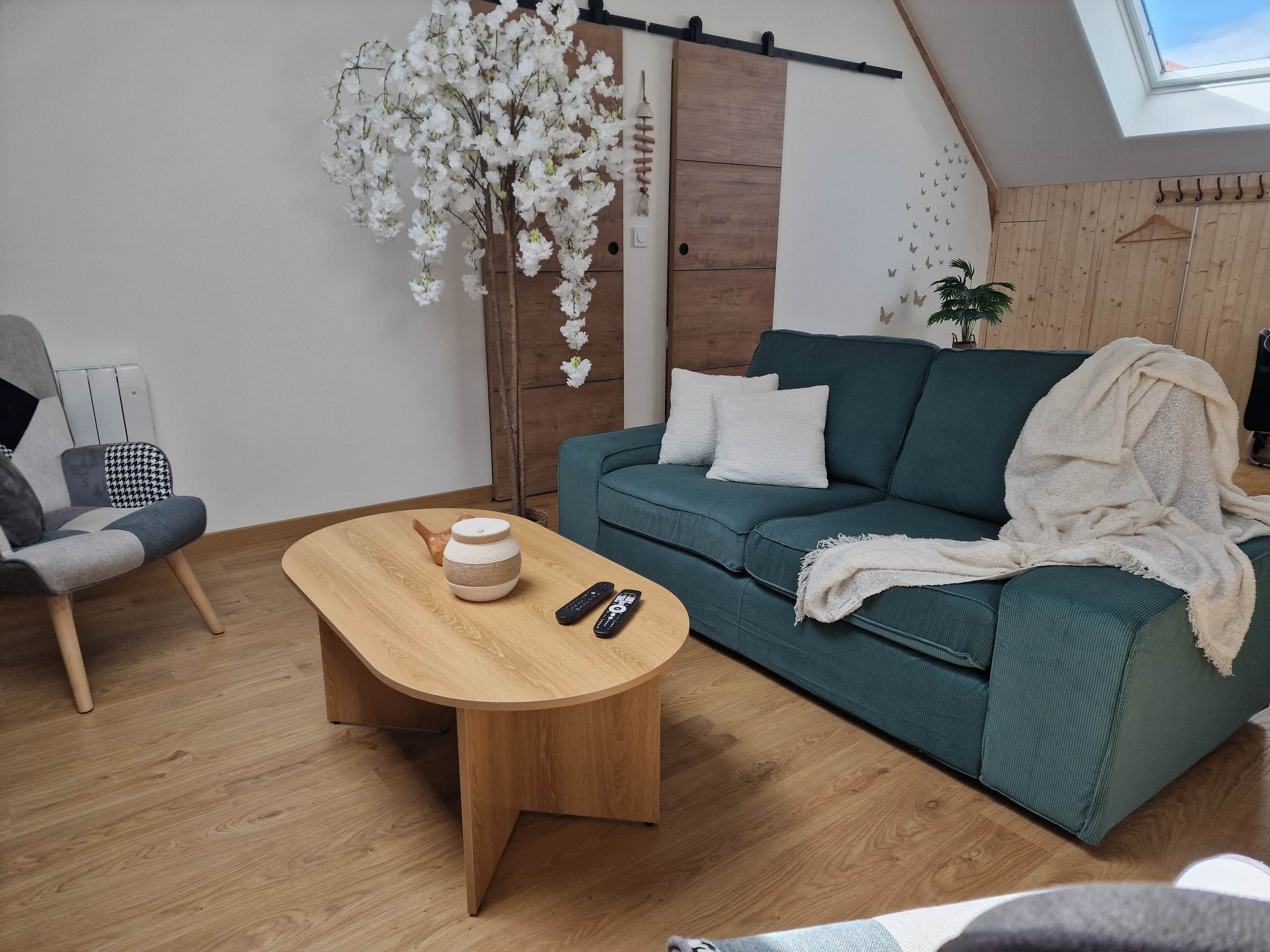 Un soggiorno moderno con un divano verde, un tavolino in legno e una pianta decorativa.