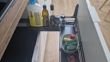 Une cuisine équipée d’un four encastré, d’un four à micro-ondes et d’un plan de travail sur lequel se trouvent divers ustensiles, notamment des bouteilles, un égouttoir et un torchon.