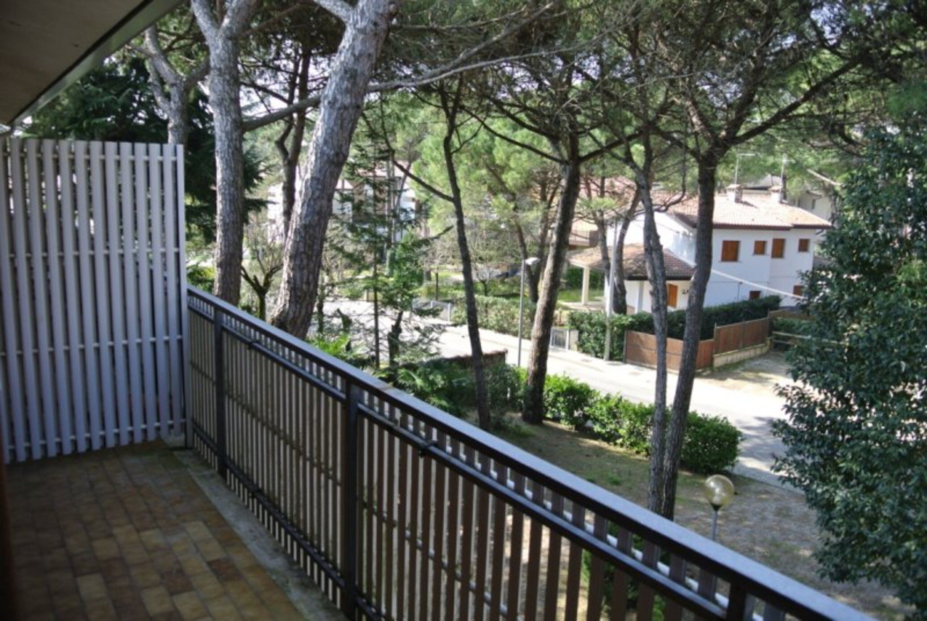 Ein Balkon mit Blick auf eine Wohngegend, einem weißen Zaun und Bäume.