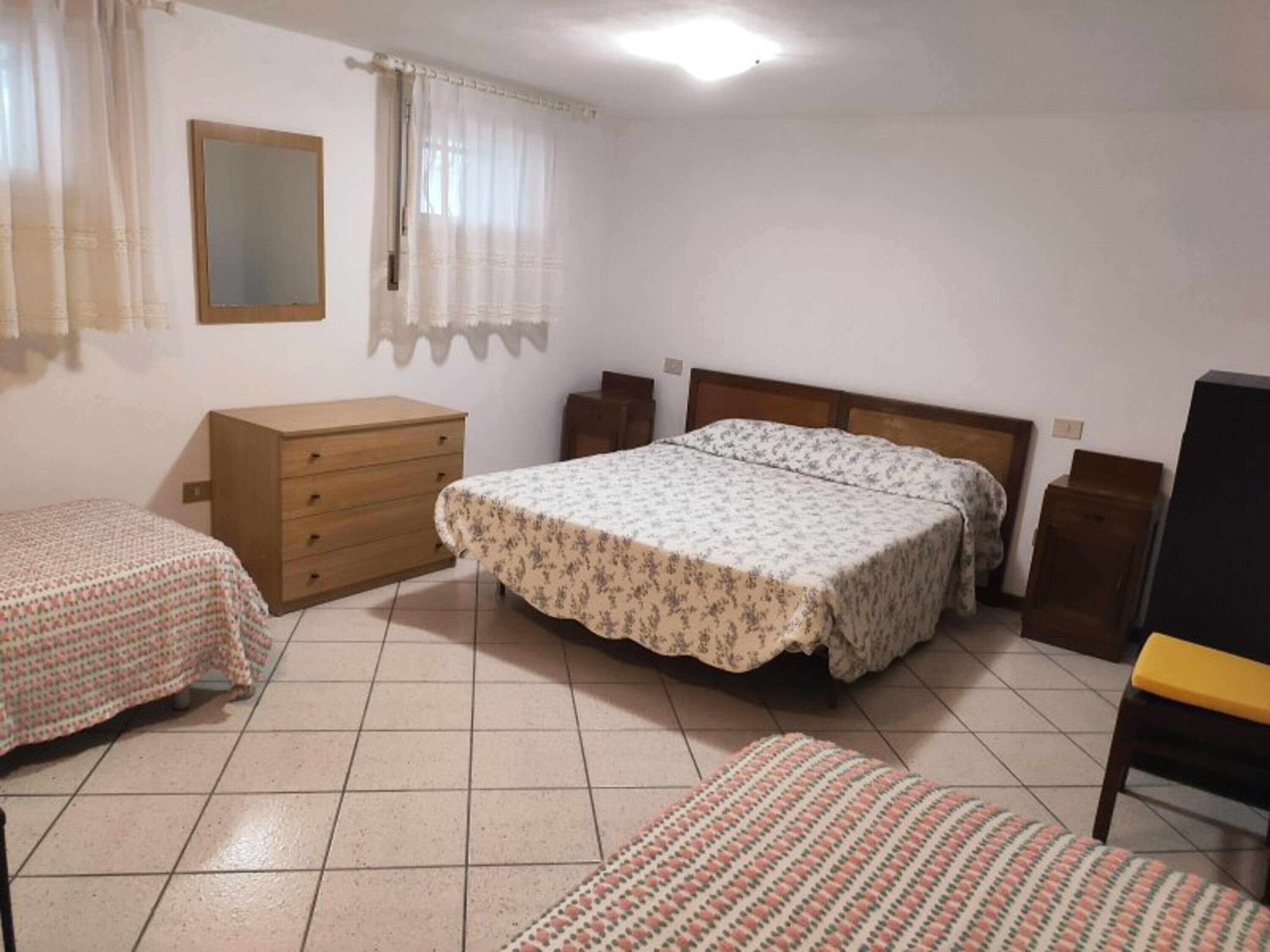 A bedroom with a bed, two bedside tables, a dresser, and a mirror.