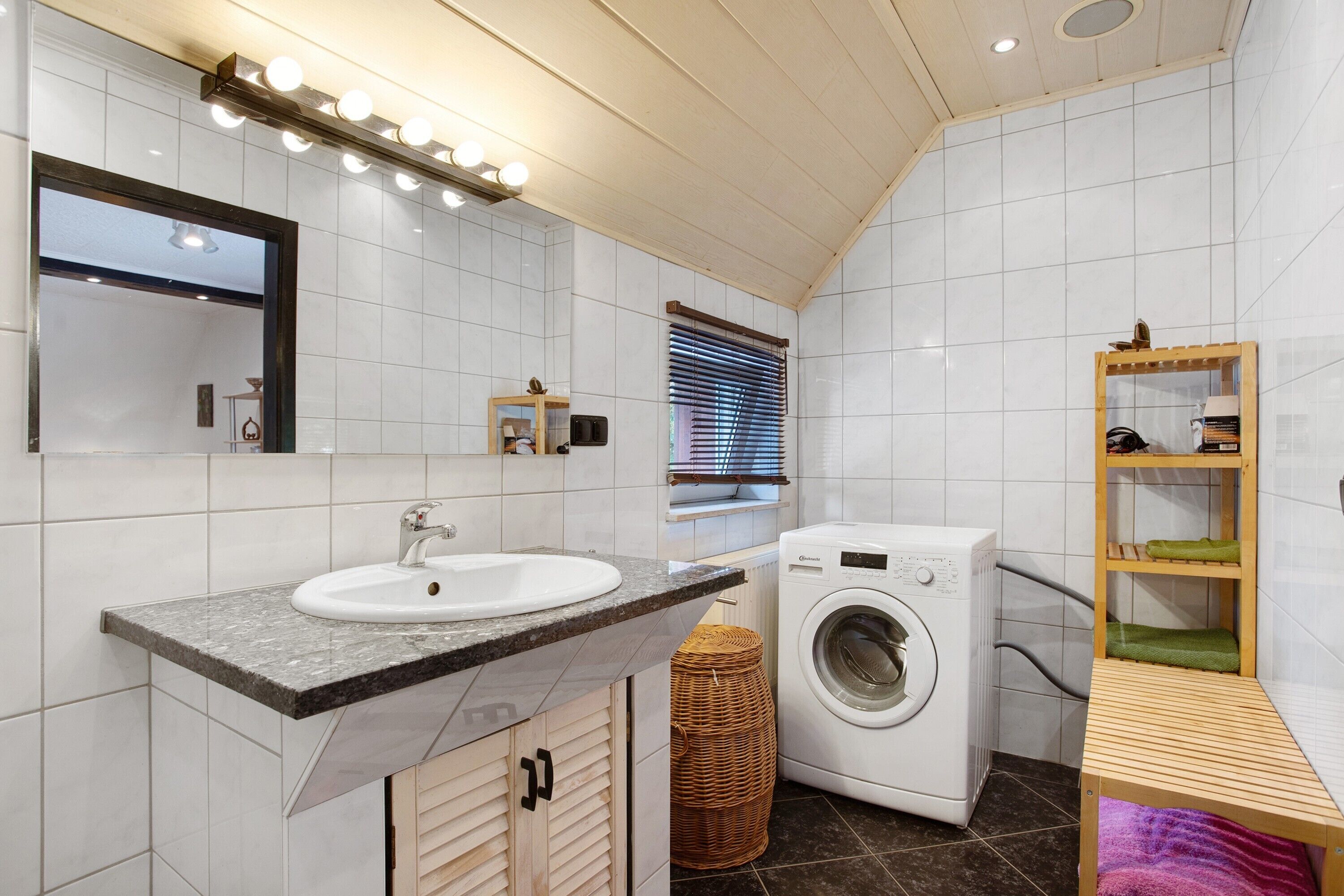 Ein modernes Badezimmer mit Waschbecken, Spiegel und Waschmaschine.