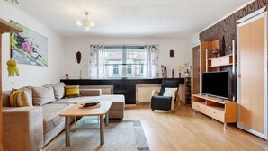 A modern living room with a sofa, coffee table, TV stand, and a view of the outside.