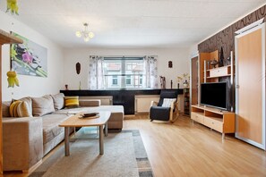 Ein modernes Wohnzimmer mit Sofa, Couchtisch, TV-Möbel und Blick ins Freie.