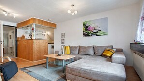 A modern living room with a sofa, a small table, and a kitchen area with wooden cabinets.