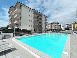 Ein Swimmingpool mit Liegestühlen und einem Gebäude mit Balkonen.