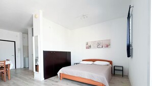 Ein Schlafzimmer mit einem Bett, einem Kleiderschrank, einem Schreibtisch und einem Stuhl.