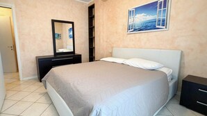 Un dormitorio con una cama, un tocador, un espejo y un cuadro colgado en la pared.