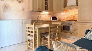 Una cocina compacta con armarios de madera, microondas, estufa y comedor con sillas.