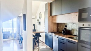 Uma cozinha moderna com armários escuros, bancada de madeira e eletrodomésticos de aço inoxidável.