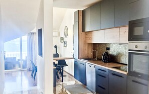 A modern kitchen with dark cabinets, a wooden countertop, and stainless steel appliances. - Stunning home in Omis (Omis)