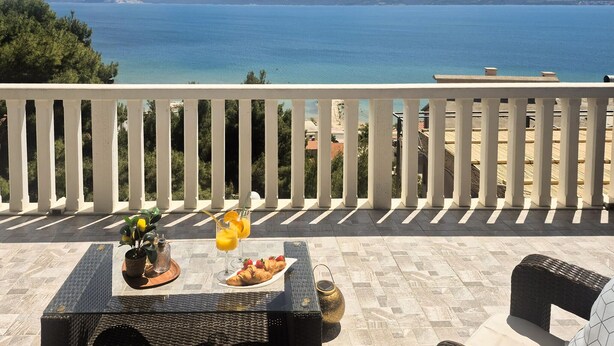 Varanda com mesa posta para o café da manhã, com vista para o mar.