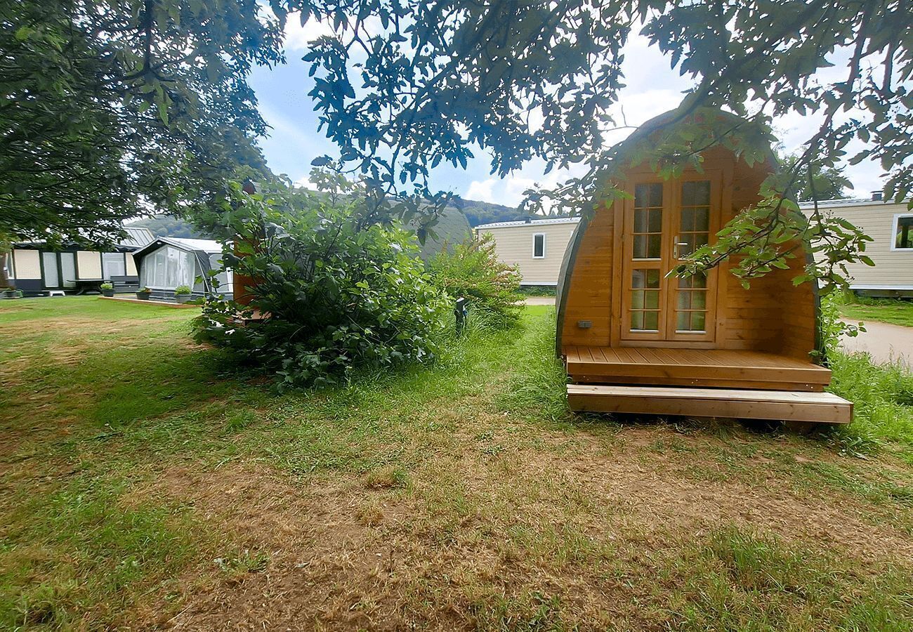 Une cabane en bois avec un porche, entourée d’herbe et d’arbres.