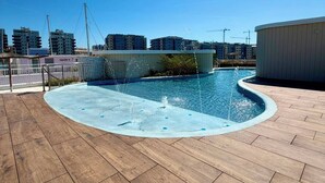 Una piscina con cubierta de madera, rodeada de edificios.