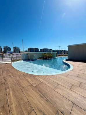 Una piscina con cubierta de madera, rodeada de edificios.