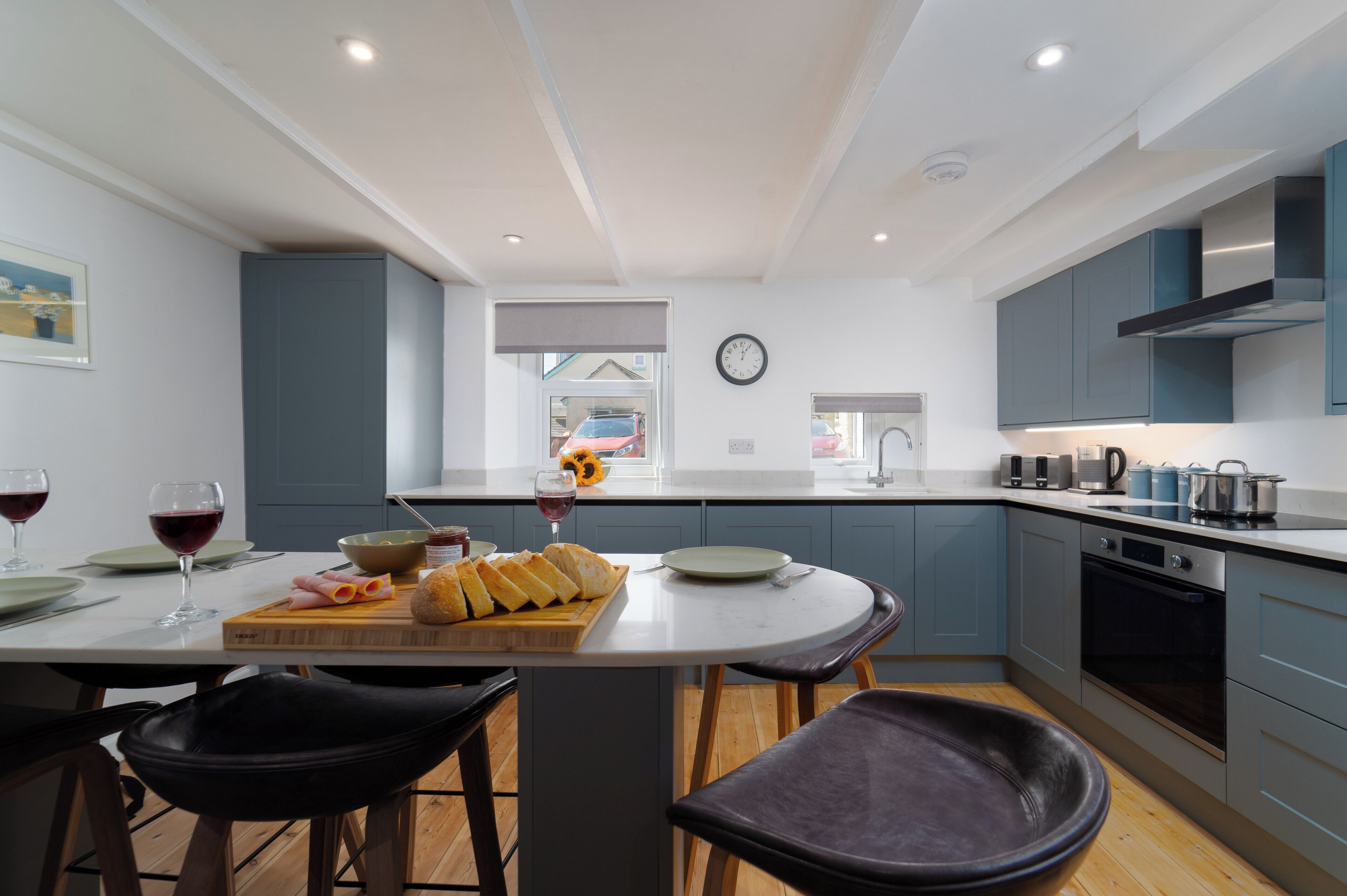 A modern kitchen with a central island, bar stools, and a view of the street.