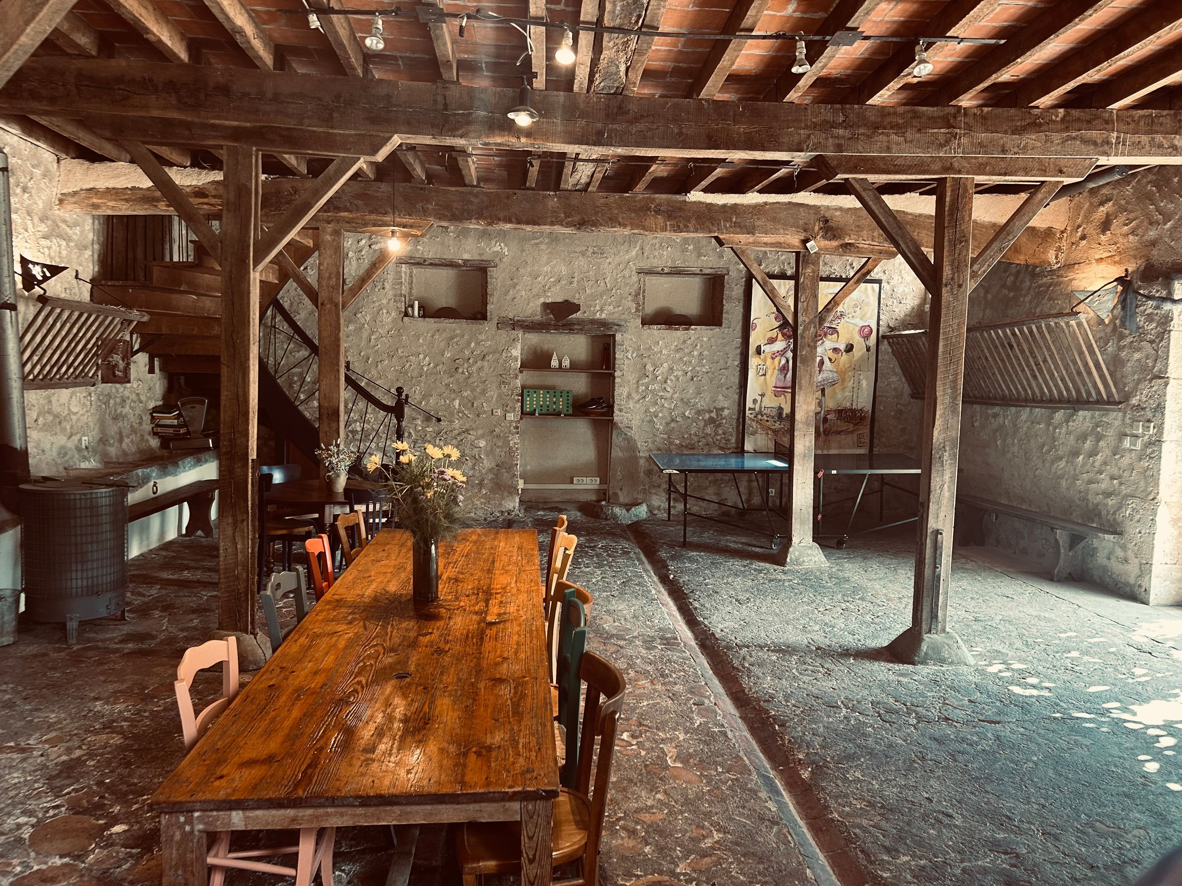 A rustic dining area with a wooden table and chairs, stone walls, and exposed wooden beams.