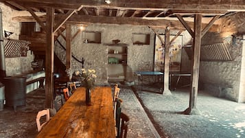 Un'accogliente sala da pranzo in stile rustico con tavolo e sedie in legno, pareti in pietra e travi a vista.