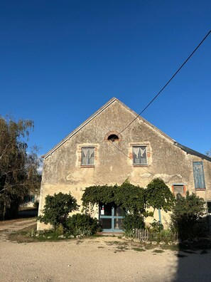 Un bâtiment à deux étages, doté d’un toit en pente, d’une fenêtre centrale en arc de cercle et d’une porte avec un panneau de verre.