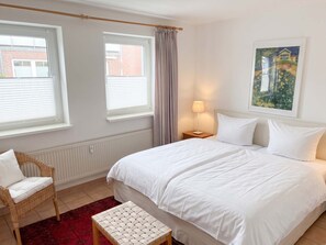 Ein Hotelzimmer mit einem Bett, einem Sessel, einem Tisch und einem Fenster mit Vorhängen.