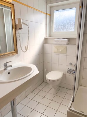 Ein Badezimmer mit Waschbecken, Toilette und einem Fenster über der Toilette.