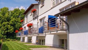 A multi-story hotel with balconies, a well-maintained lawn, and a clear sky. - FeWo Frische Brise - Lauterbach (Putbus)