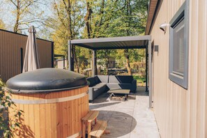 Un espacio de estar al aire libre techado con un jacuzzi, una terraza de madera y vistas a un barrio residencial.